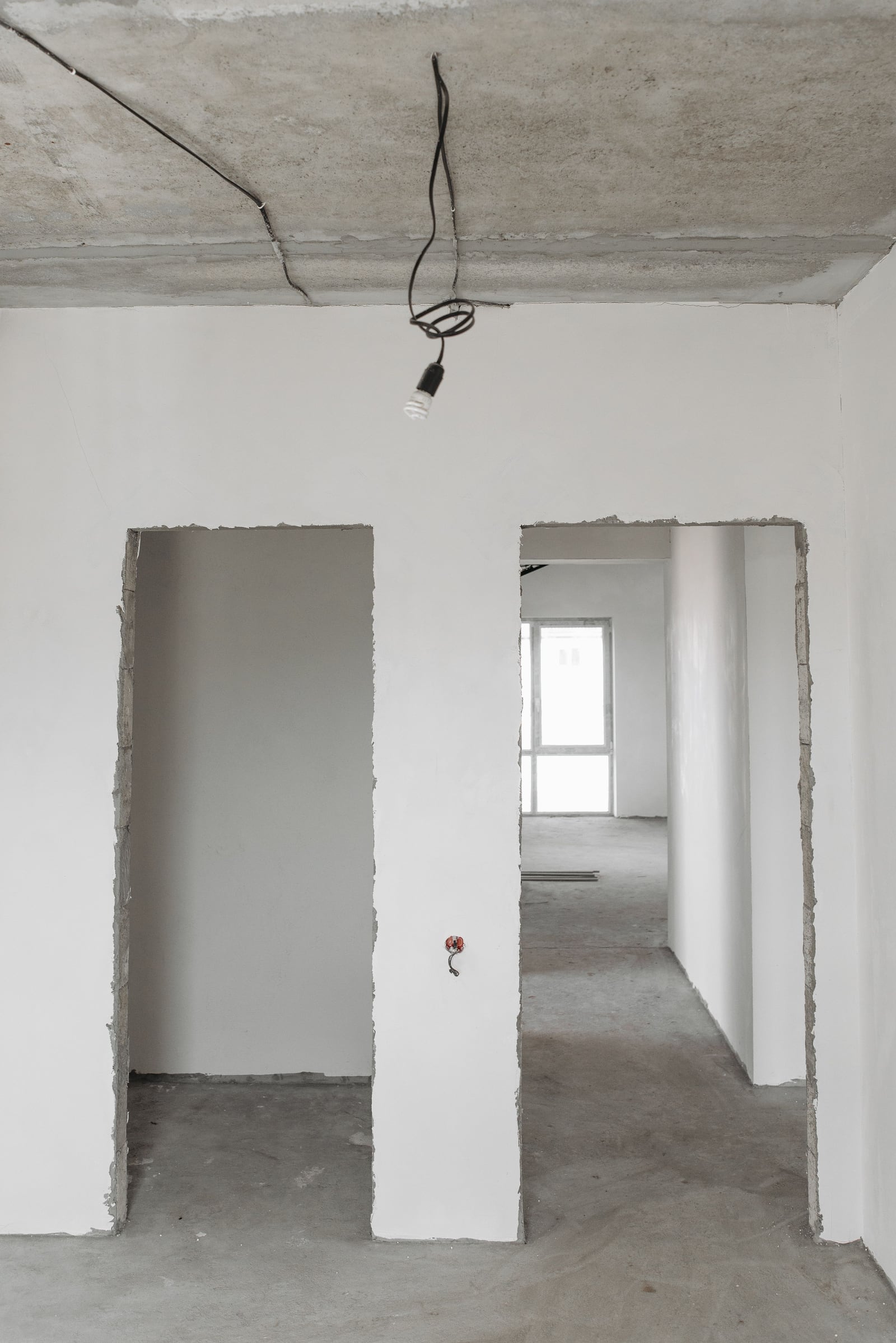 Vom Trockenbauer vorbereiteter Rohbau-Innenraum mit mehreren Türöffnungen und Betondecke